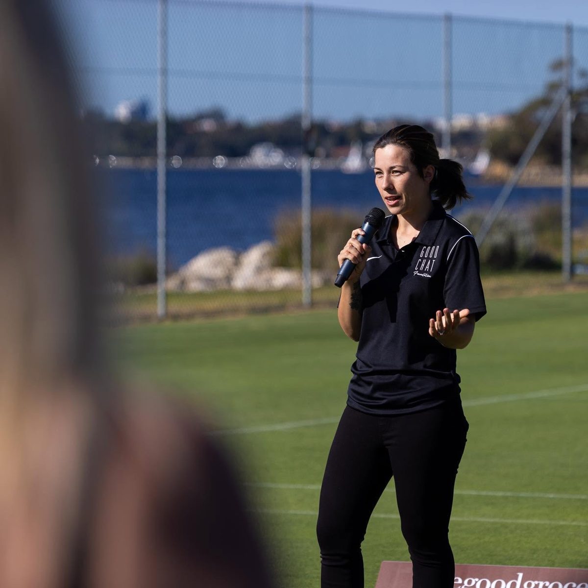 Kelly speaking with a microphone at a Good Chat Foundation event