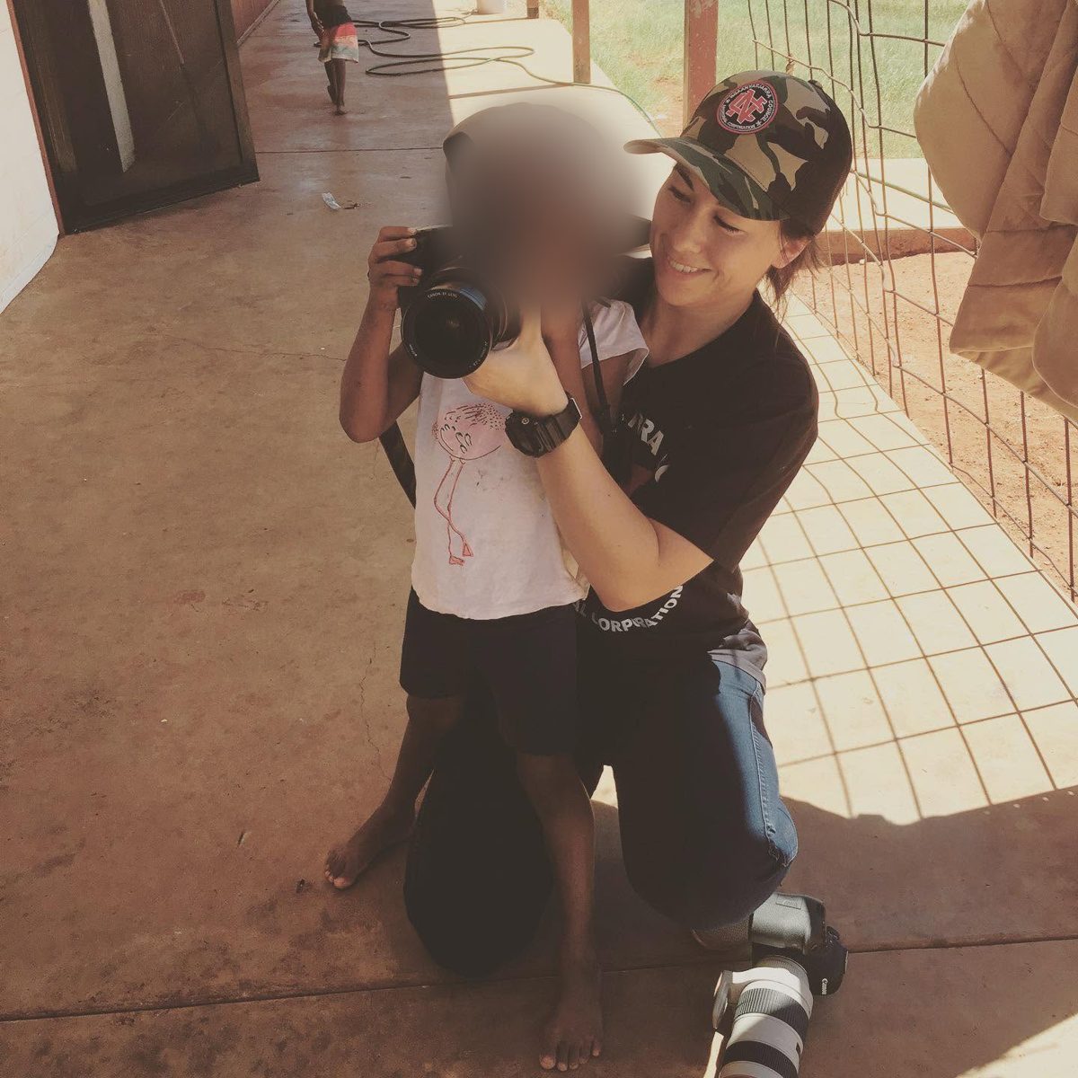 Kelly kneeling to help a young child look through a camera